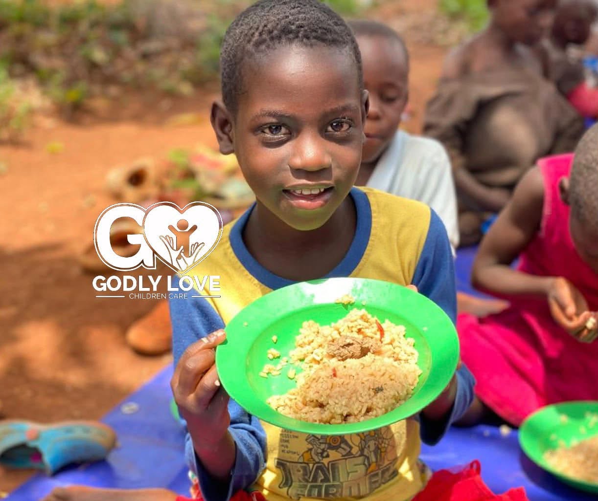 A child holding a plate of food through Godly Love Children Care, one of the African organizations supported by the Weave